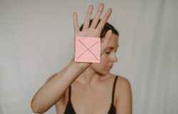 woman holding her hand out palm forward with a post it note on it showing and X